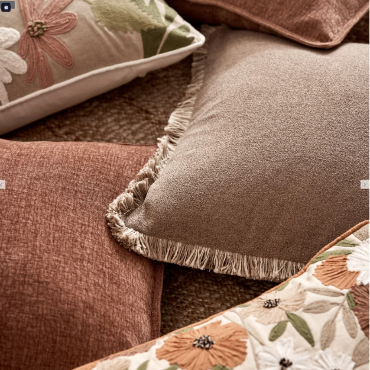 Margot truffle fringe cushion styled on a jute rug with rust and floral embroidered cushions