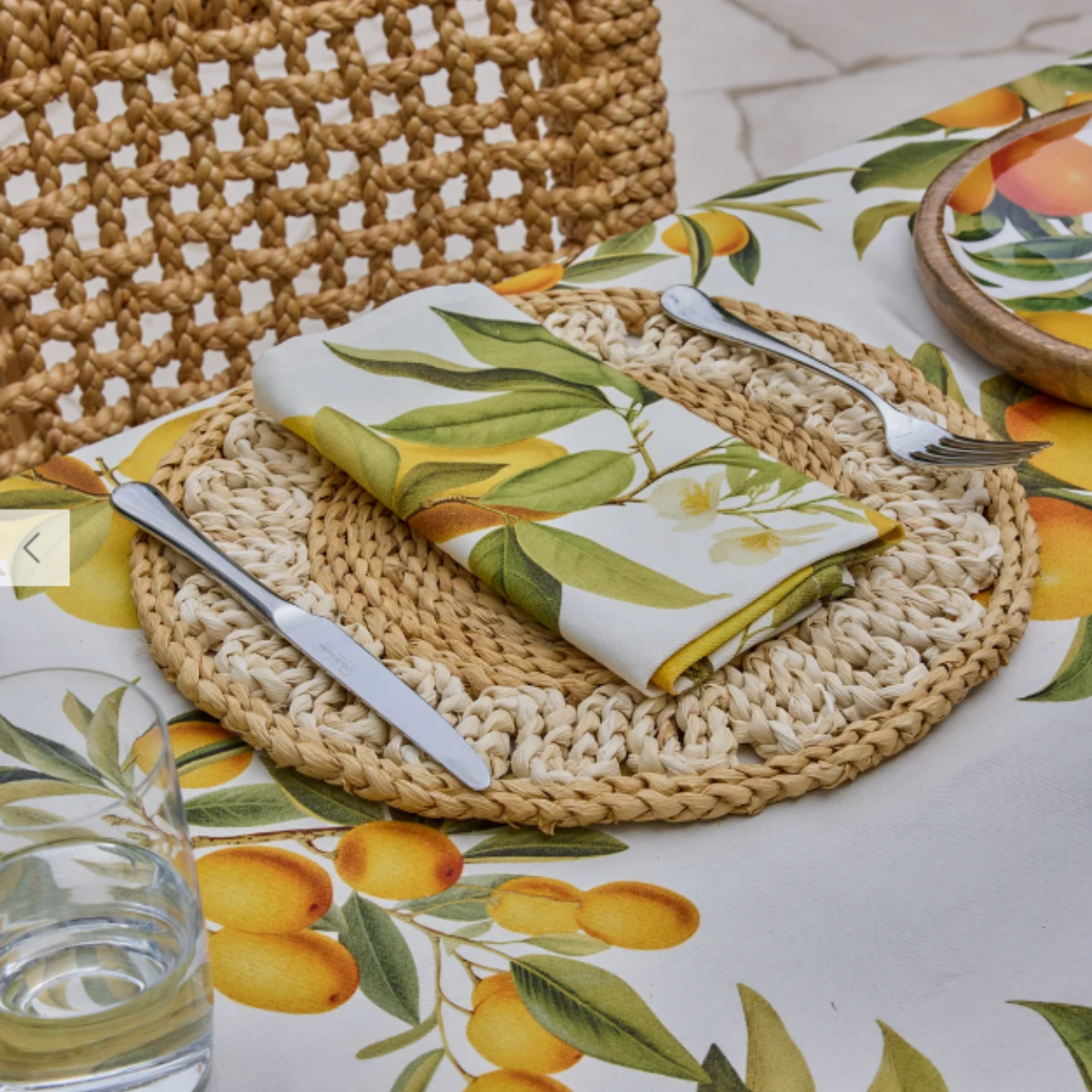 Palma braided placemat styled with a folded lemon print napkin and cutlery on a citrus tablecloth
