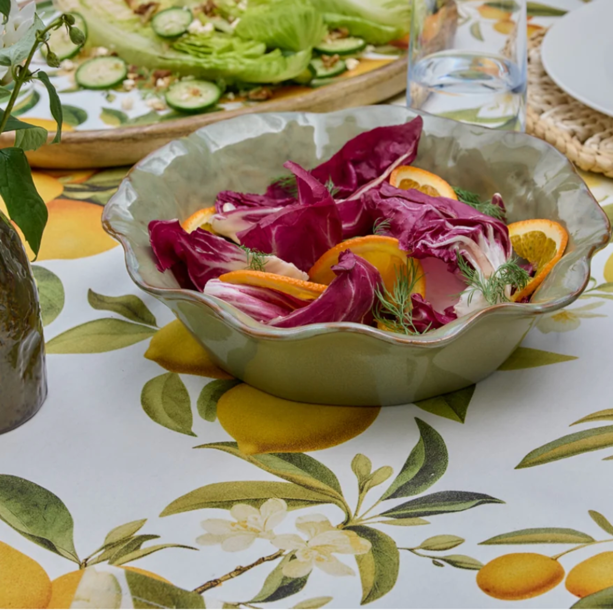 Marseille green wavy bowl filled with radicchio and orange salad on a citrus print tablecloth