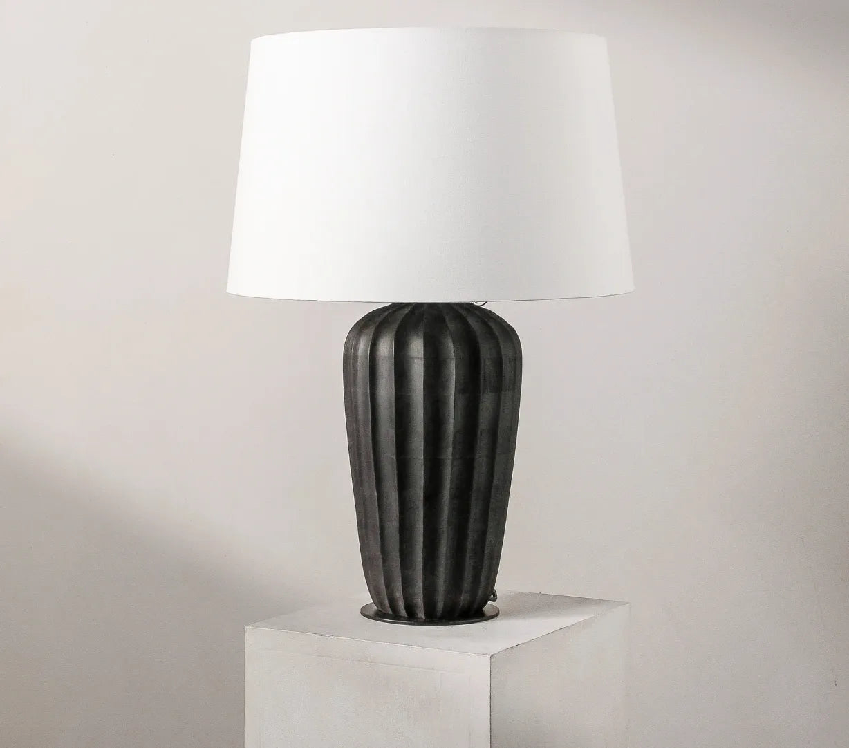 Kai table lamp with a ribbed matte black wood base and natural cotton shade