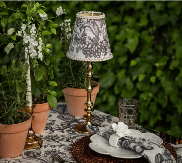 Luxe & Beau black toile lamp shade on a brass base, styled on an outdoor dining table – alternate view