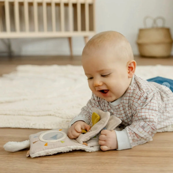 Baby holding the ecru sheep soft book, showing its size in small hands