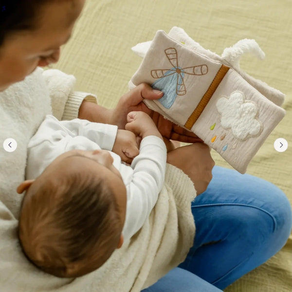 Baby turning the crinkle pages of the ecru sheep soft book