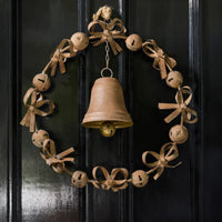 Thumbnail for Bow & Bell Christmas Wreath in aged rust iron hanging on a black front door, a ring of jingle bells and looped bows with a large bell at the centre