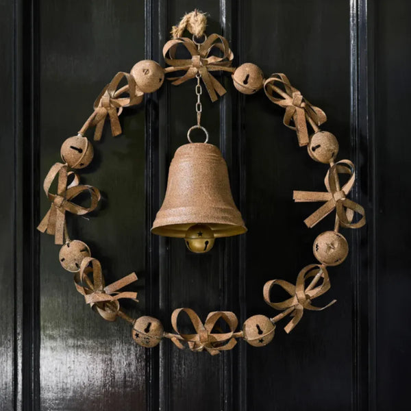 Bow & Bell Christmas Wreath in aged rust iron hanging on a black front door, a ring of jingle bells and looped bows with a large bell at the centre
