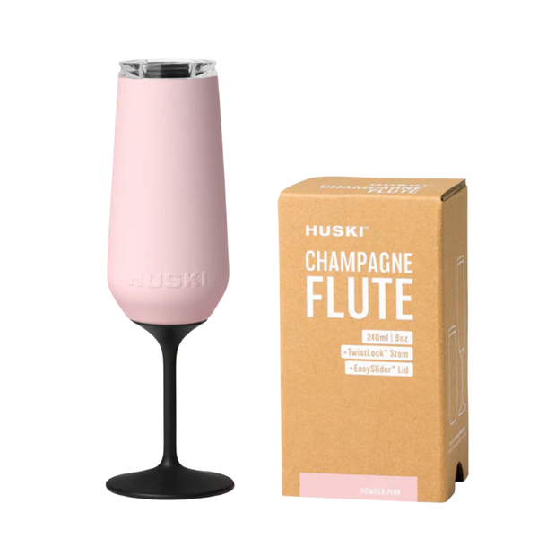 Pink champagne flute with black base next to its packaging box on a white background