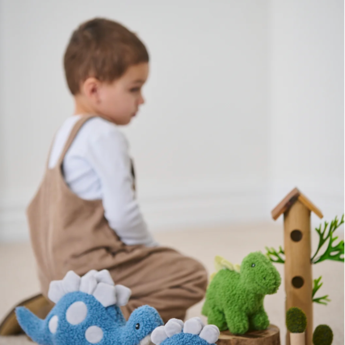 Child playing with Stu the Stegosaurus blue soft toy by Nana Huchy