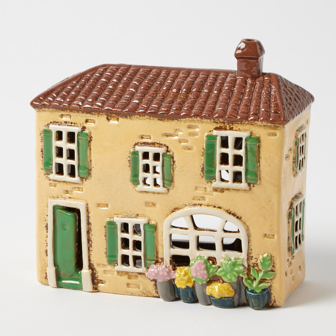 Meadow Lane tealight holder, soft yellow stoneware village house with potted flowers