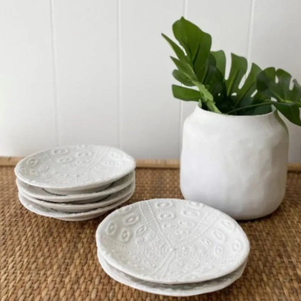 Stack of sea urchin plates styled on a woven placemat beside a white vase